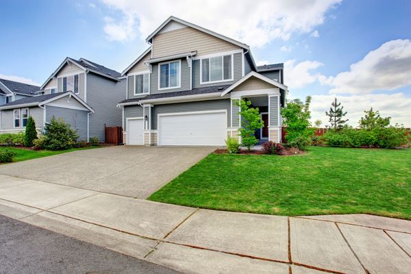 A large house with a white garage door and a large driveway.