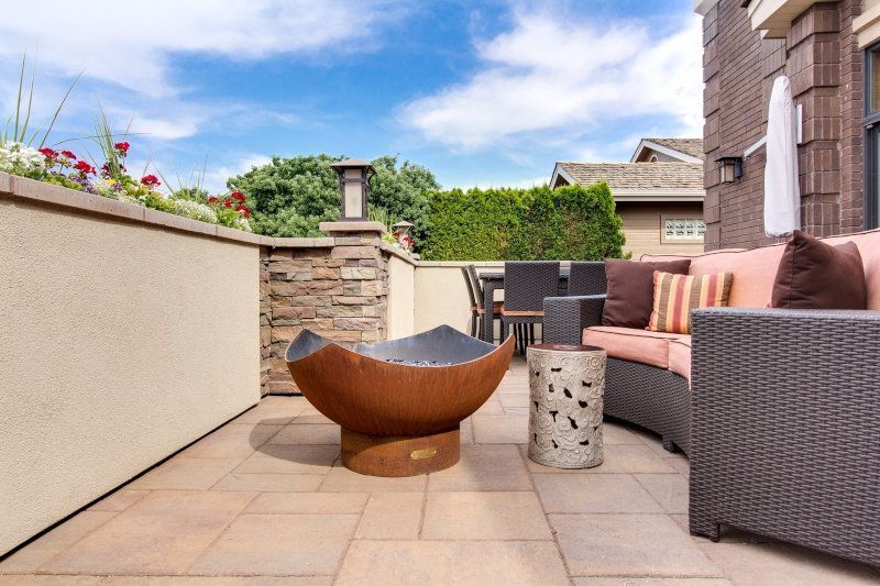 There is a fire pit on the patio with a couch and chairs. Patio expertly paved by Cornflower Driveways in Doncaster.