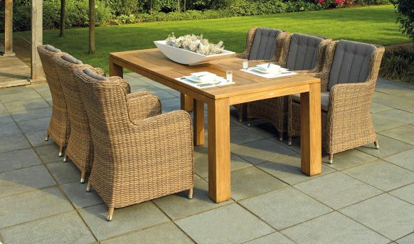 A wooden table with wicker chairs on a patio. Patio expertly paved by Cornflower Driveways in Doncaster.