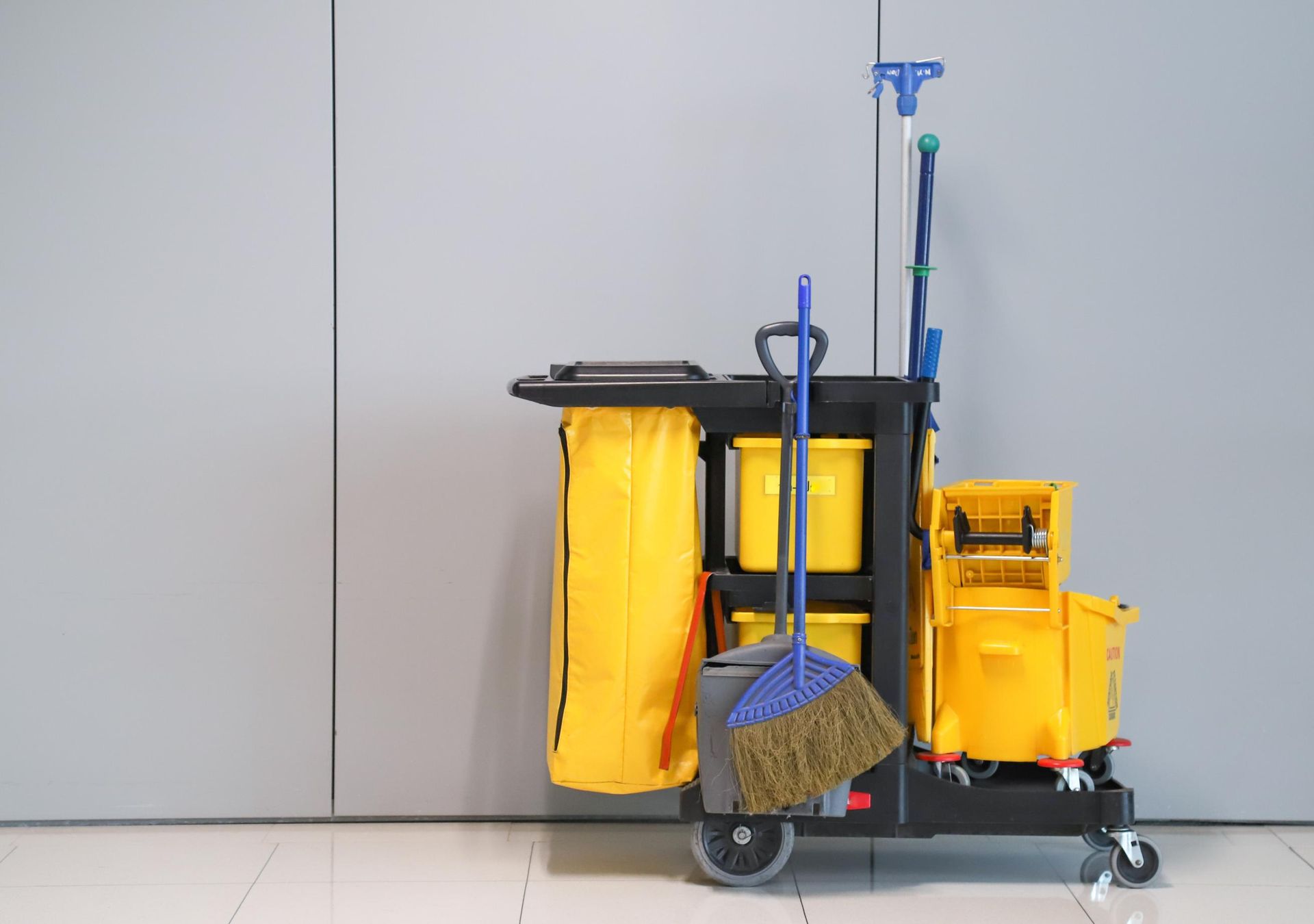 Cleaning cart with yellow buckets, bags, and tools.