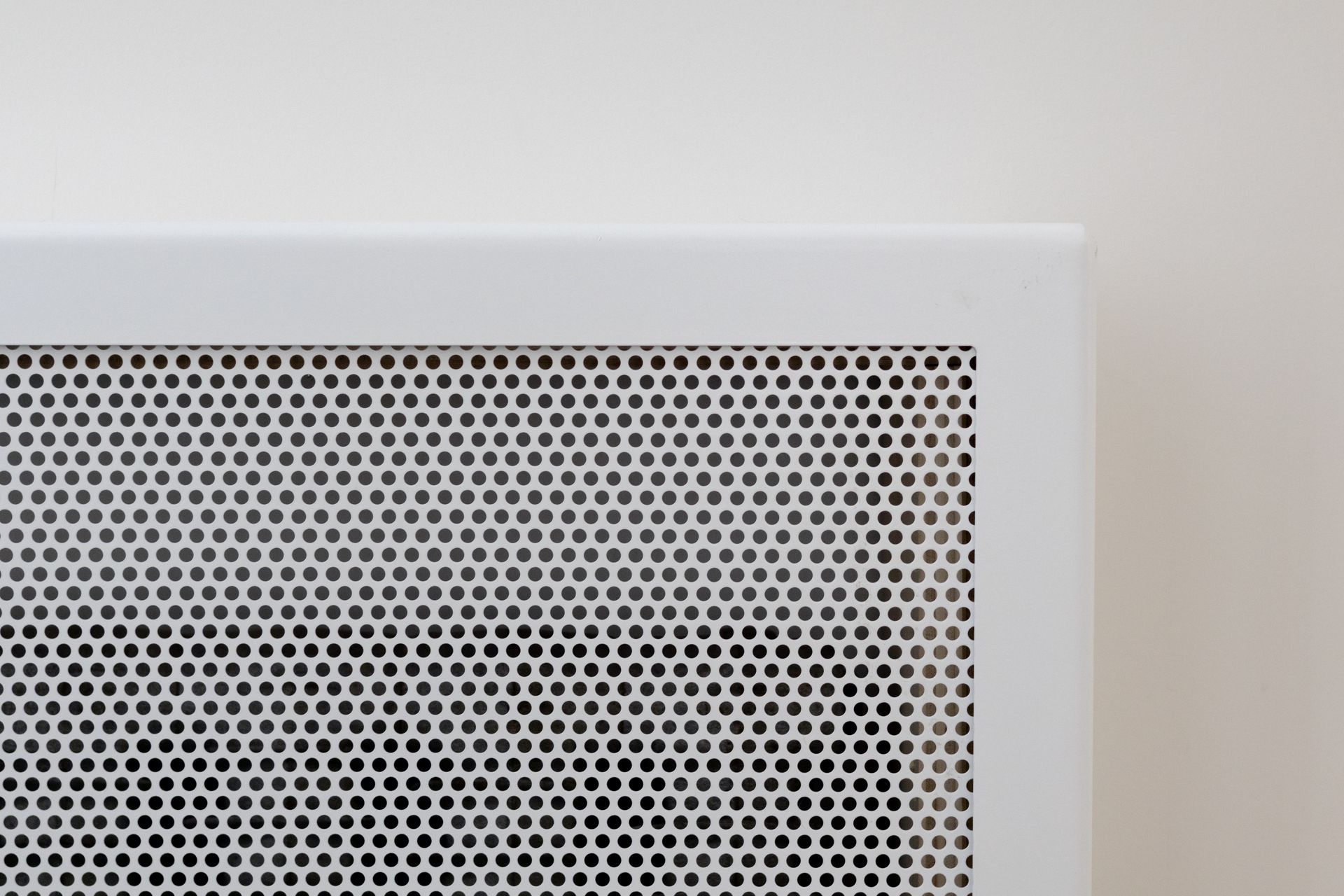 Grille d'aération en métal blanc avec motif perforé.