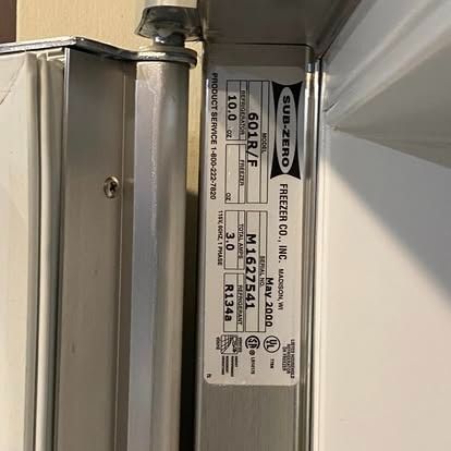 A metal plate on a Sub-Zero freezer door showing model 601R/F, serial number M1627541, and manufacture date May 2000.