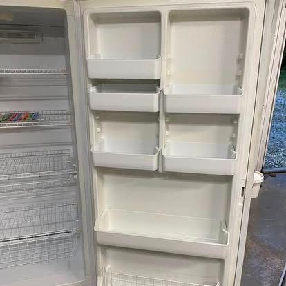 The open white door and interior of an empty refrigerator, featuring multiple shelves and storage compartments.