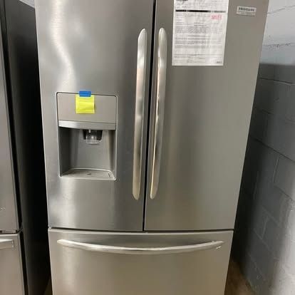 Stainless steel French-door refrigerator with a water and ice dispenser, featuring a yellow sticky note on the panel.