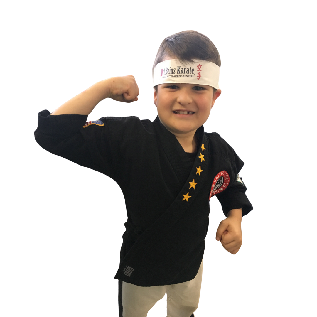 a boy with a yellow belt is pointing at the camera