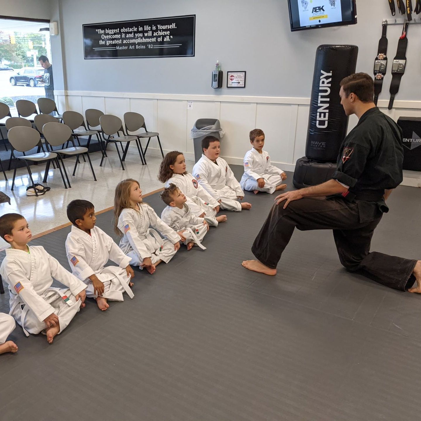 a group of children are practicing karate with a teacher in a gym .