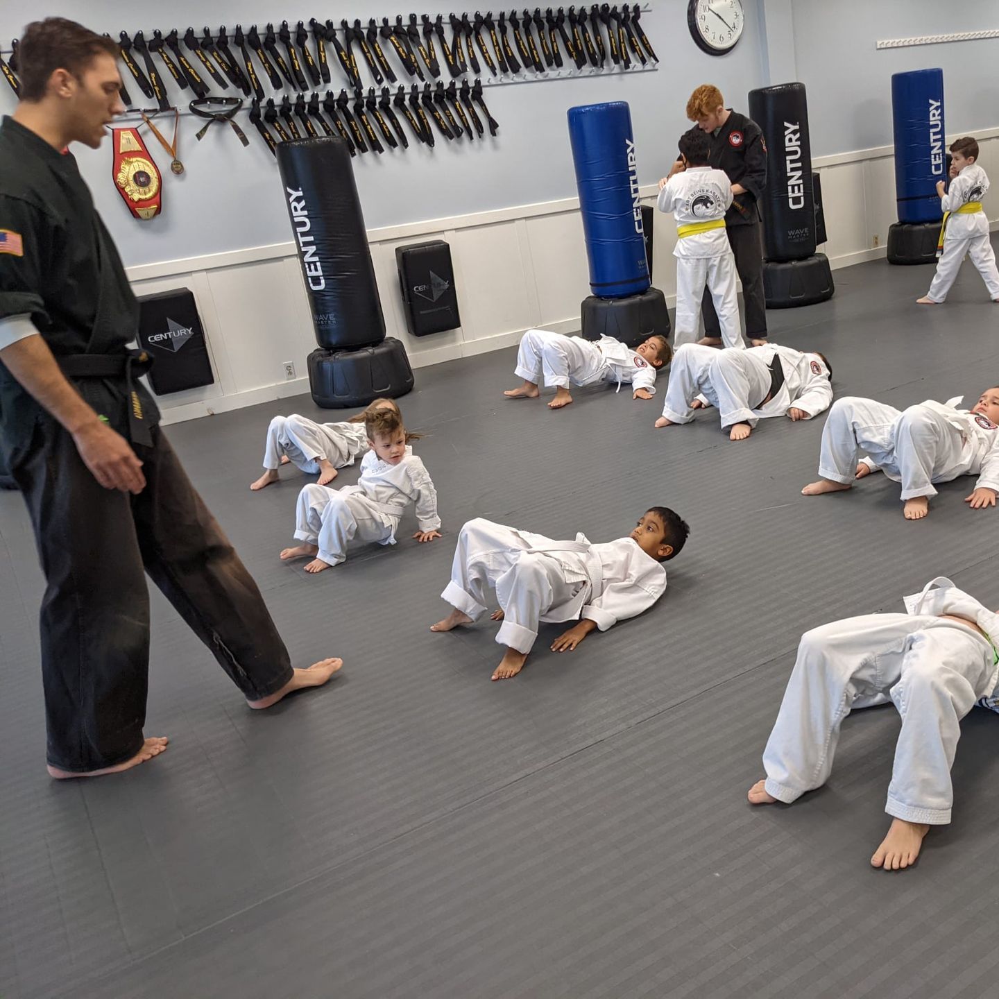 a young girl in a karate uniform is sitting on the floor .