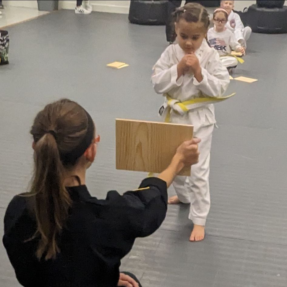 A group of young girls are practicing karate in a gym.