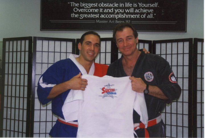 Three young boys in white karate uniforms pose for a picture