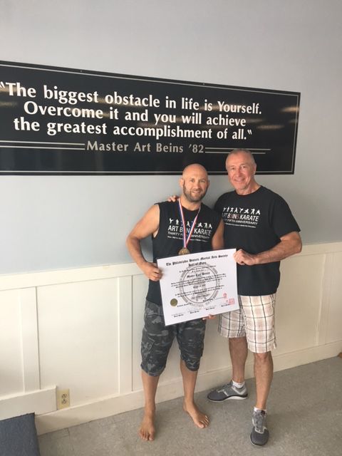 Three young boys in white karate uniforms pose for a picture