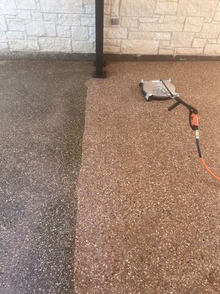 A person is cleaning a concrete floor with a machine.