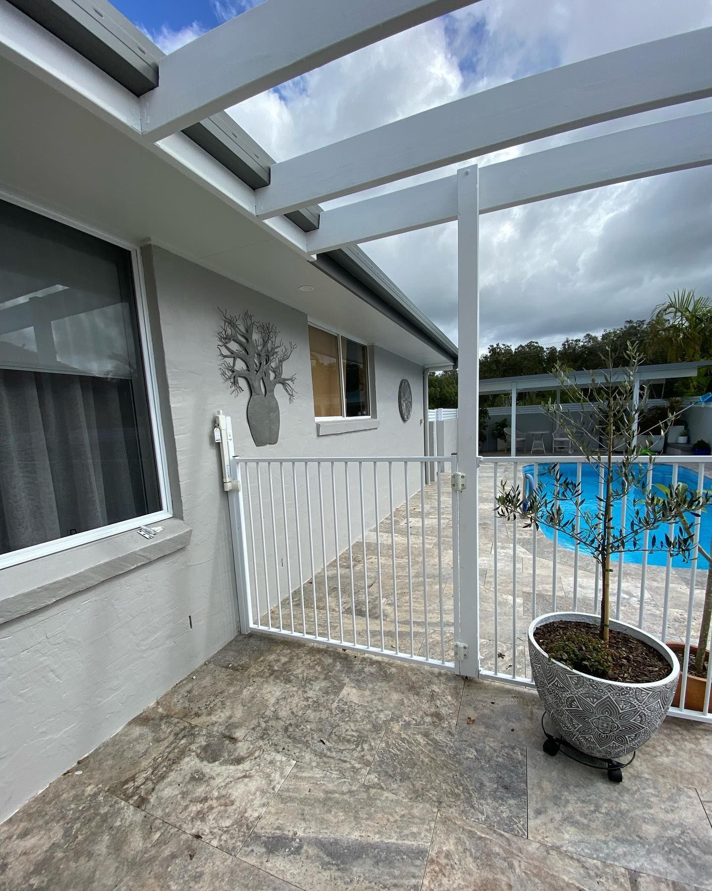 A White House With a Fence and a Potted Plant in Front of It — Fence & Deck Australia Pty Ltd in Lennox Head, NSW