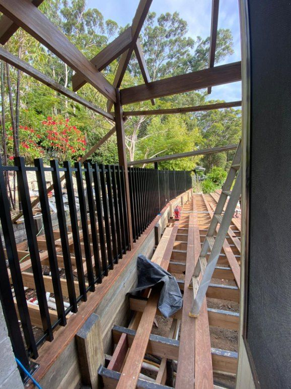 A Wooden Deck With a Black Railing is Being Built — Fence & Deck Australia Pty Ltd in Casino, NSW