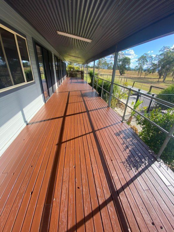 A Long Wooden Deck With a Metal Roof and Railing — Fence & Deck Australia Pty Ltd in Casino, NSW