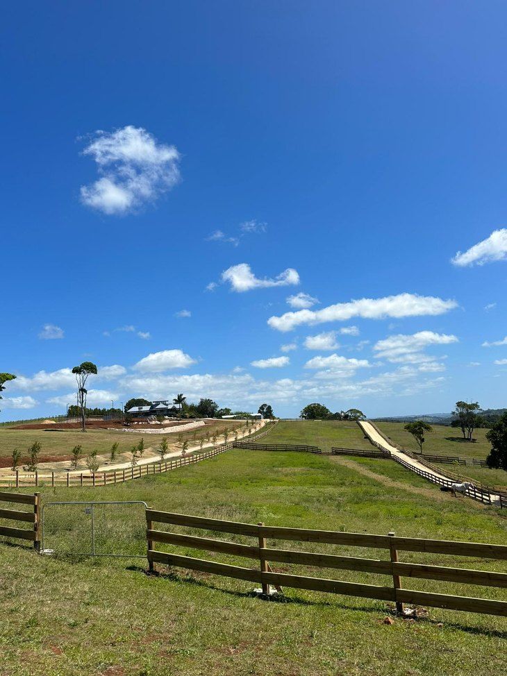 A Wooden Fence Surrounds a Grassy Field on a Sunny Day — Fence & Deck Australia Pty Ltd in Casino, NSW