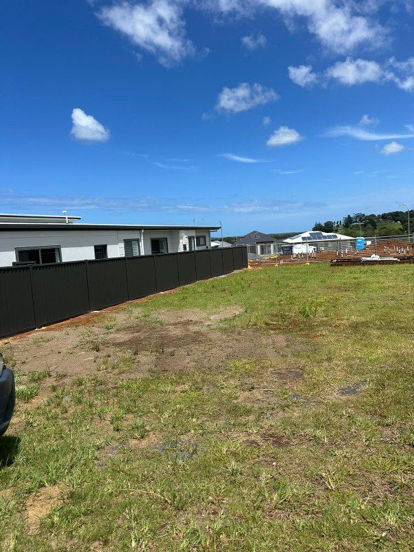 A Large Grassy Field With a Black Fence and a House in the Background — Fence & Deck Australia Pty Ltd in Casino, NSW
