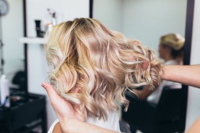 A woman is getting her hair done by a hairdresser in a salon.