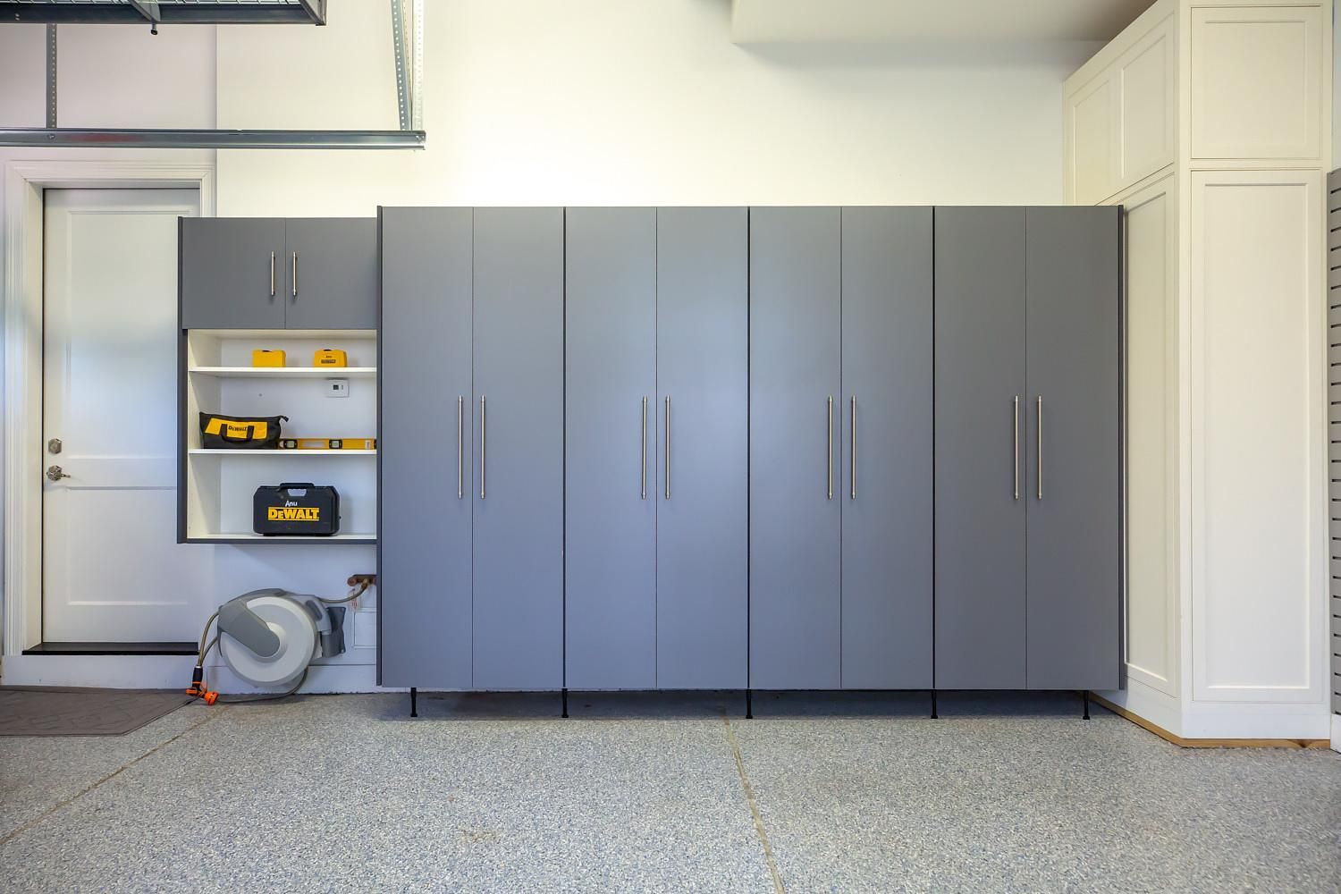 A garage with a lot of cabinets and a hose on the floor.