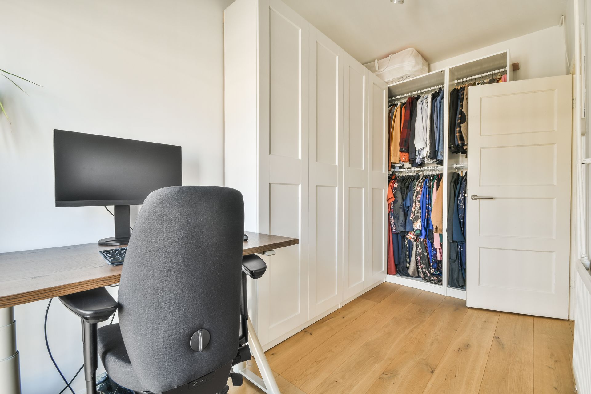 A walk in closet with lots of shelves and drawers and a blue ottoman.