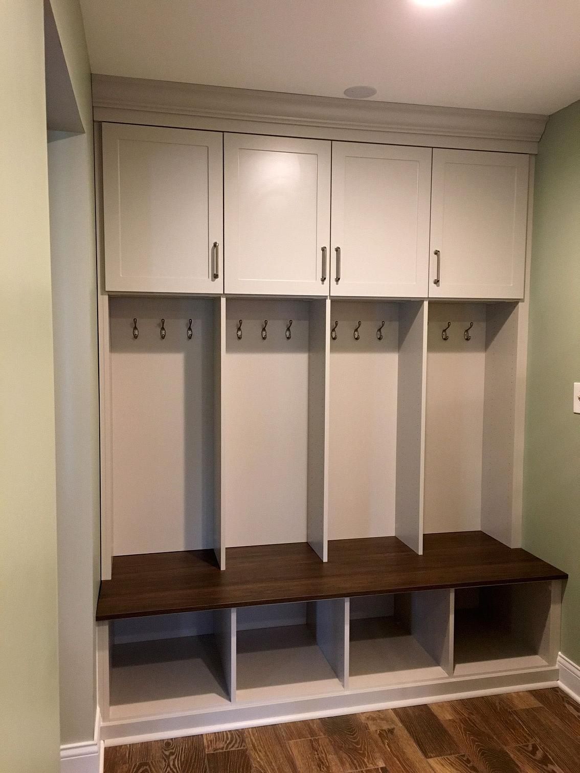 A mud room with white cabinets and a wooden bench.
