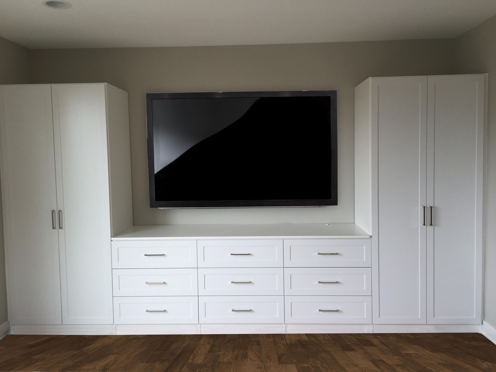 A large flat screen tv is mounted on the wall above a dresser.