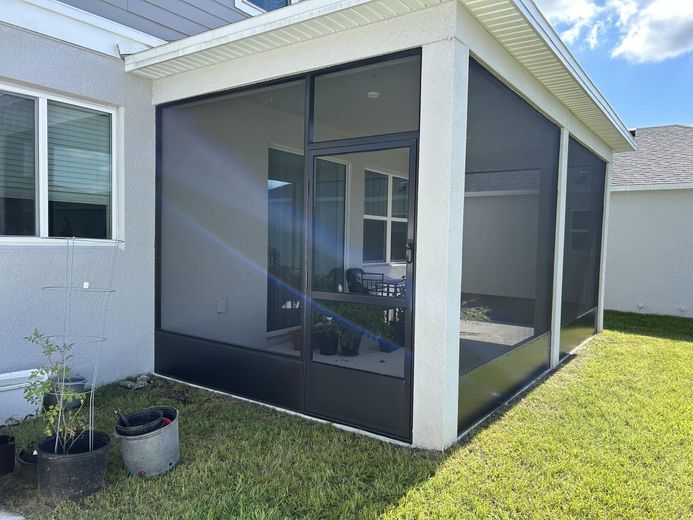 A screened in porch in the backyard of a house.