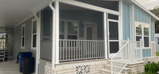 A mobile home with a screened in porch and stairs.