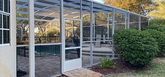 A screened in porch with a swimming pool in the background.