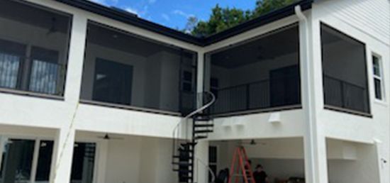 A large white house with screened in porches and a spiral staircase.