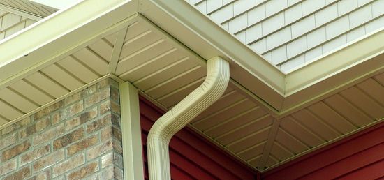 A close up of a gutter on the side of a house.