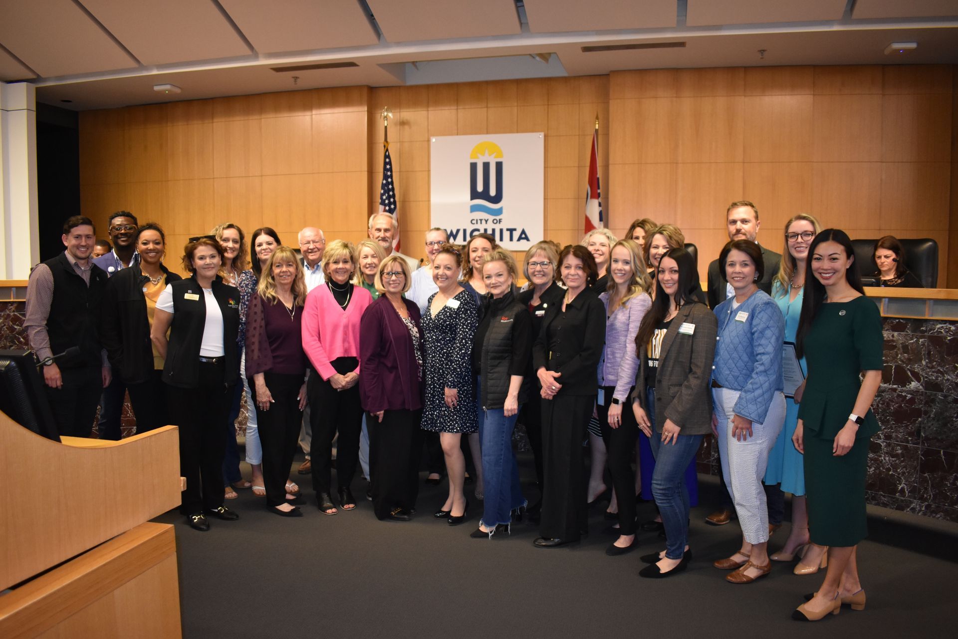 A group of people are putting their hands together on a wooden table.