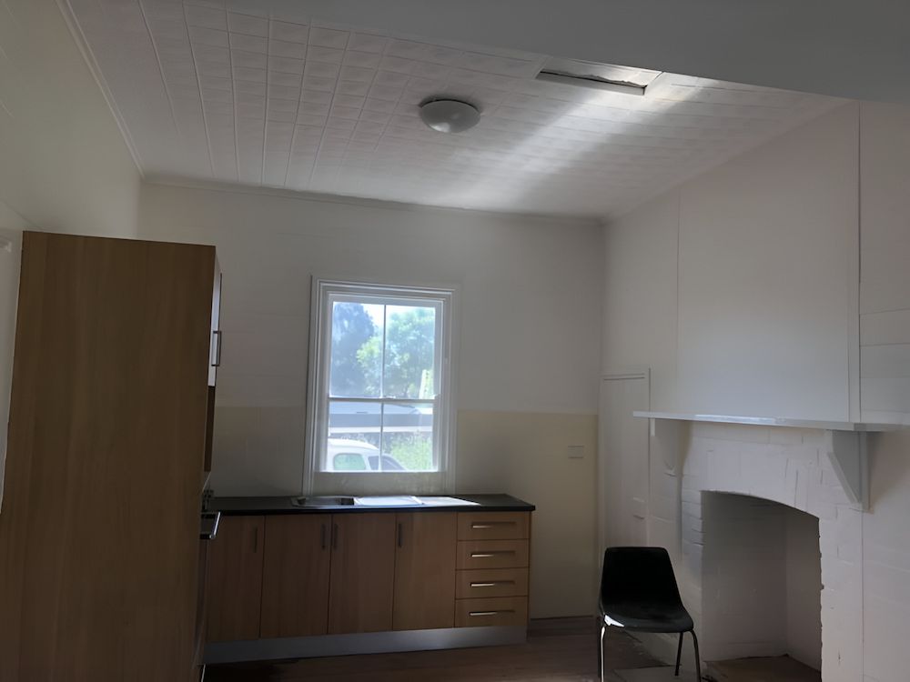 An Empty Kitchen With Wooden Cabinets And A Fireplace — L & S Wirth Painting in Dubbo, NSW