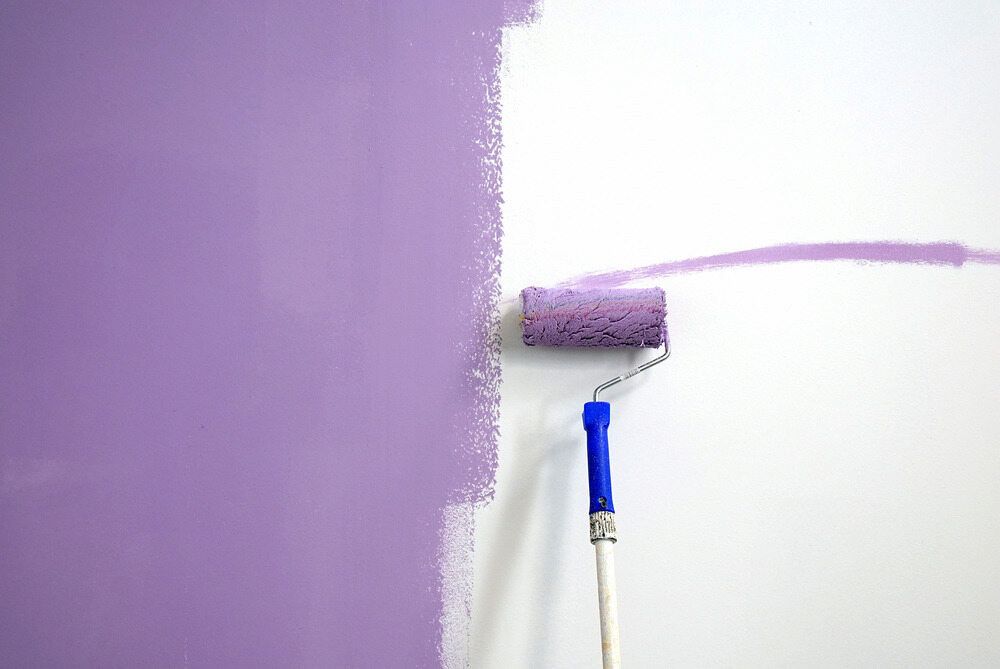 A Purple Paint Roller Is Being Used To Paint A White Wall — L & S Wirth Painting in Cobar, NSW