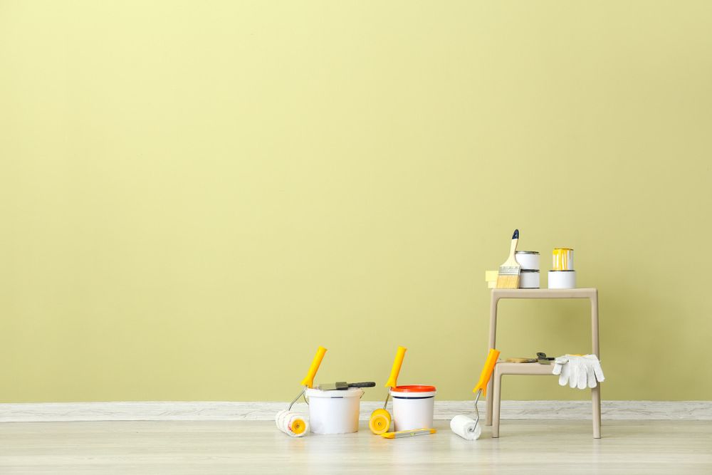 A Room With A Yellow Wall And A Ladder With Paint Buckets And Rollers On It — L & S Wirth Painting in Cobar, NSW
