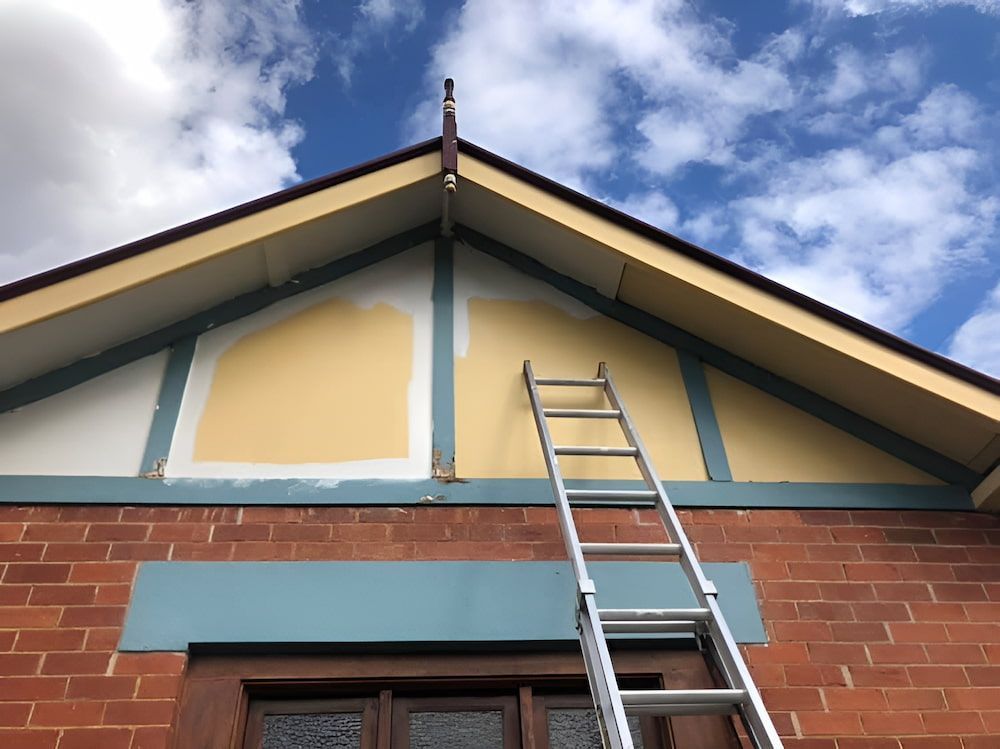A Ladder Is Hanging From The Roof Of A Brick Building — L & S Wirth Painting in Dubbo, NSW