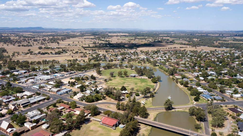 An Aerial View Of A Small Town With A Bridge Over A River — L & S Wirth Painting in Forbes, NSW