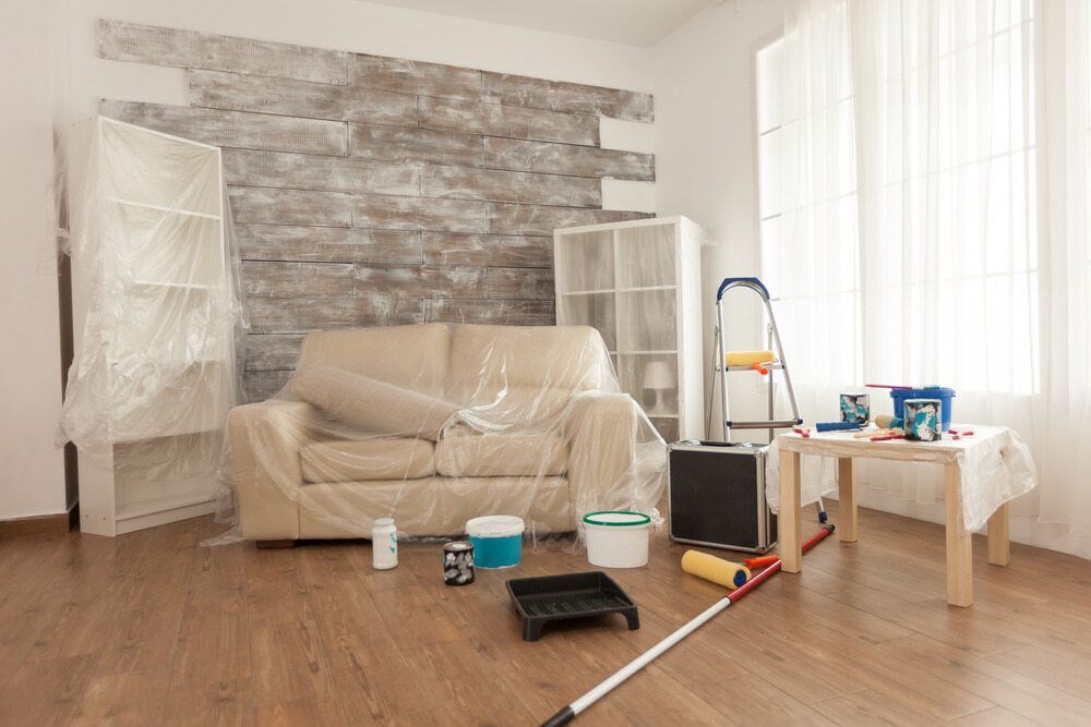 A Living Room Is Being Painted With A Couch Covered In Plastic — L & S Wirth Painting in Parkes, NSW