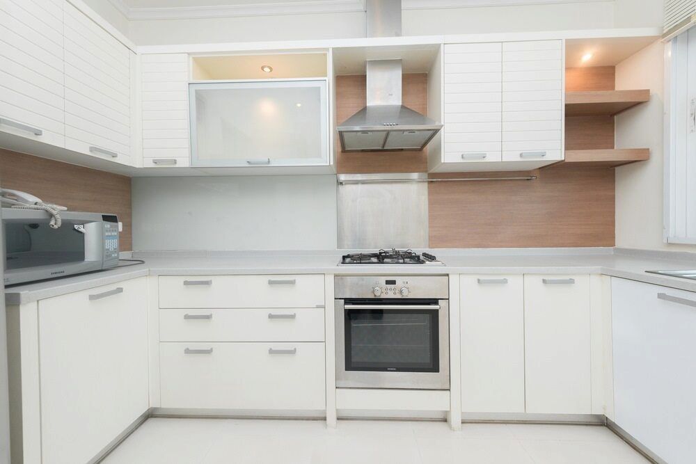 A Kitchen With White Cabinets And Stainless Steel Appliances — L & S Wirth Painting in Cobar, NSW