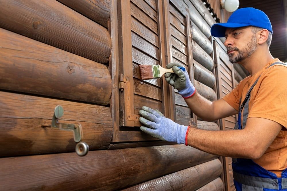 A Man Is Painting A Wooden Wall With A Brush — L & S Wirth Painting in Nyngan, NSW