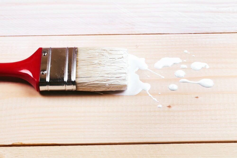 A Paint Brush With White Paint Spilling Out Of It On A Wooden Surface — L & S Wirth Painting in Dubbo, NSW