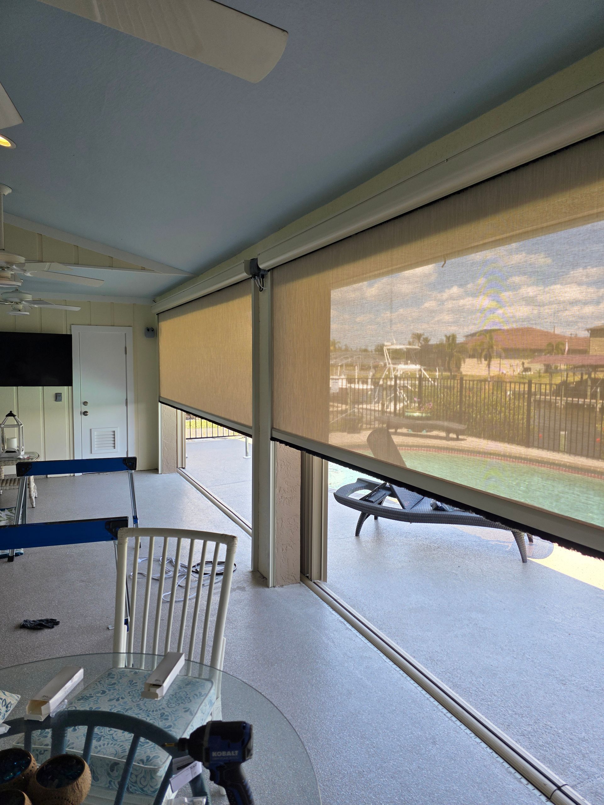 Outdoor patio with retractable sun shades overlooking a pool.