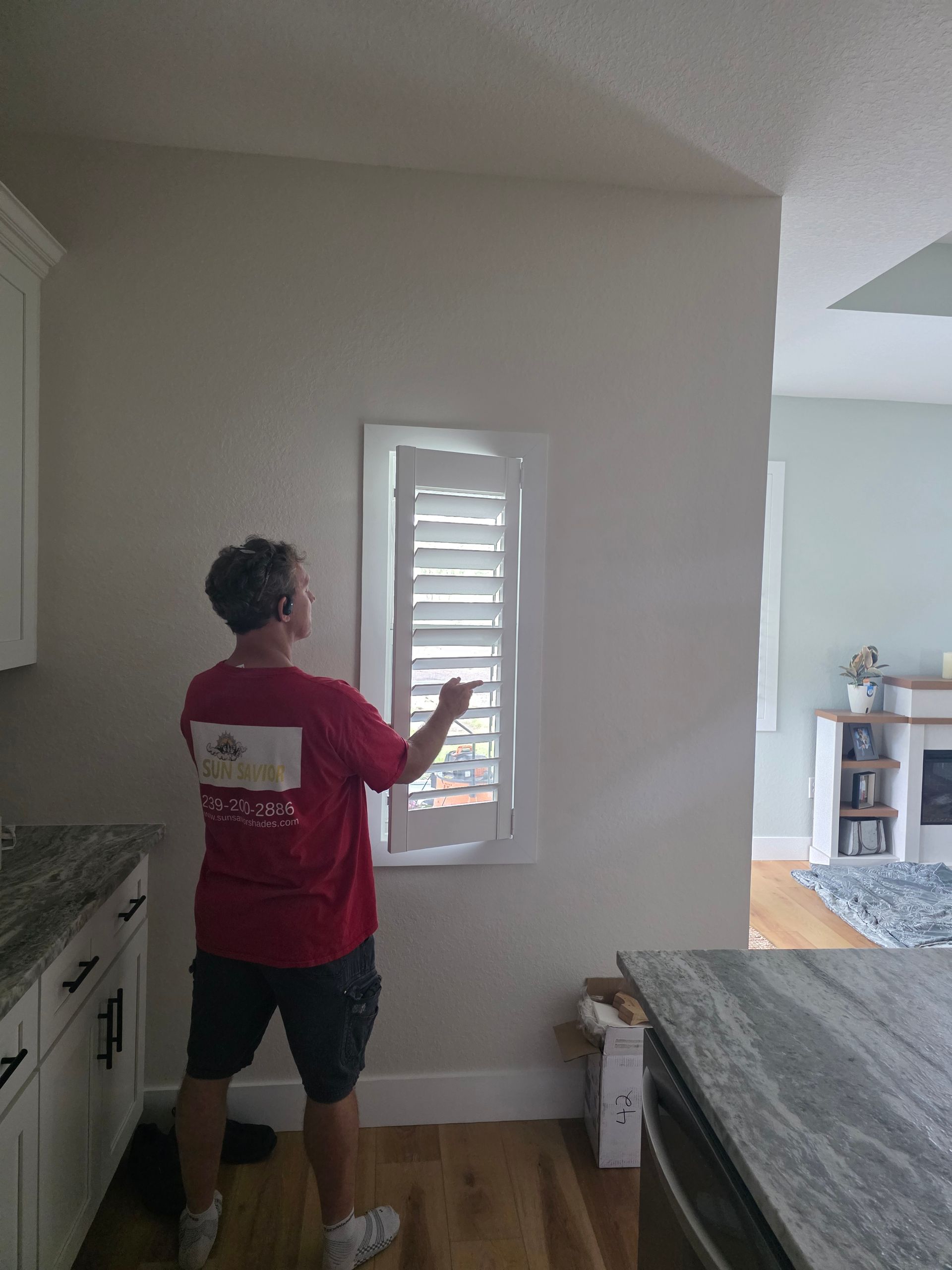 Person opening white shutters on a kitchen window.