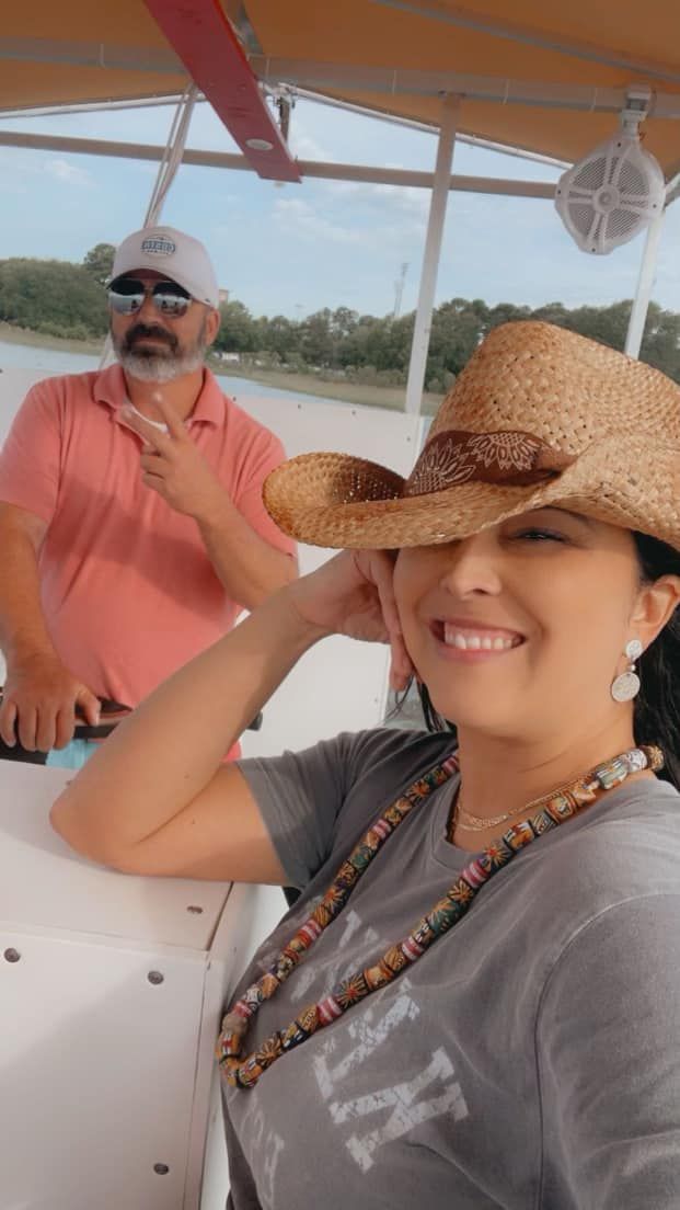 A man and a woman are sitting on a boat . the woman is wearing a cowboy hat.