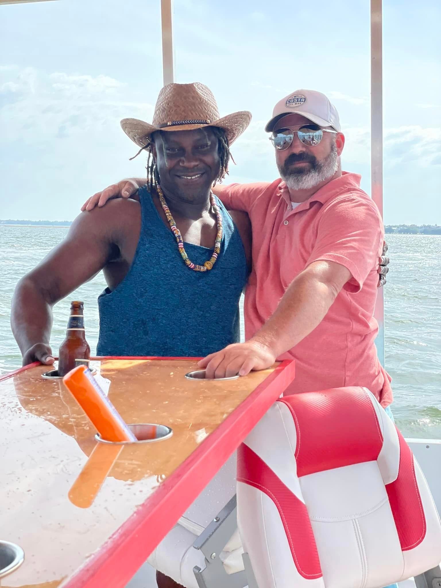 Two men are posing for a picture on a boat . one of the men is wearing a cowboy hat.