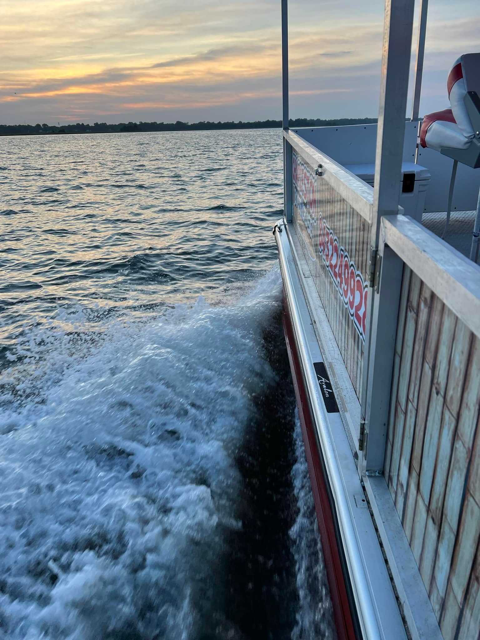 A boat is floating on top of a body of water at sunset.