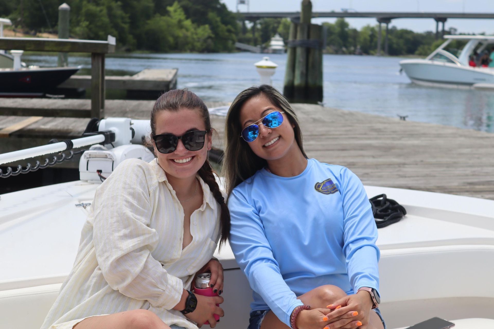 Two women are sitting on the side of a boat.