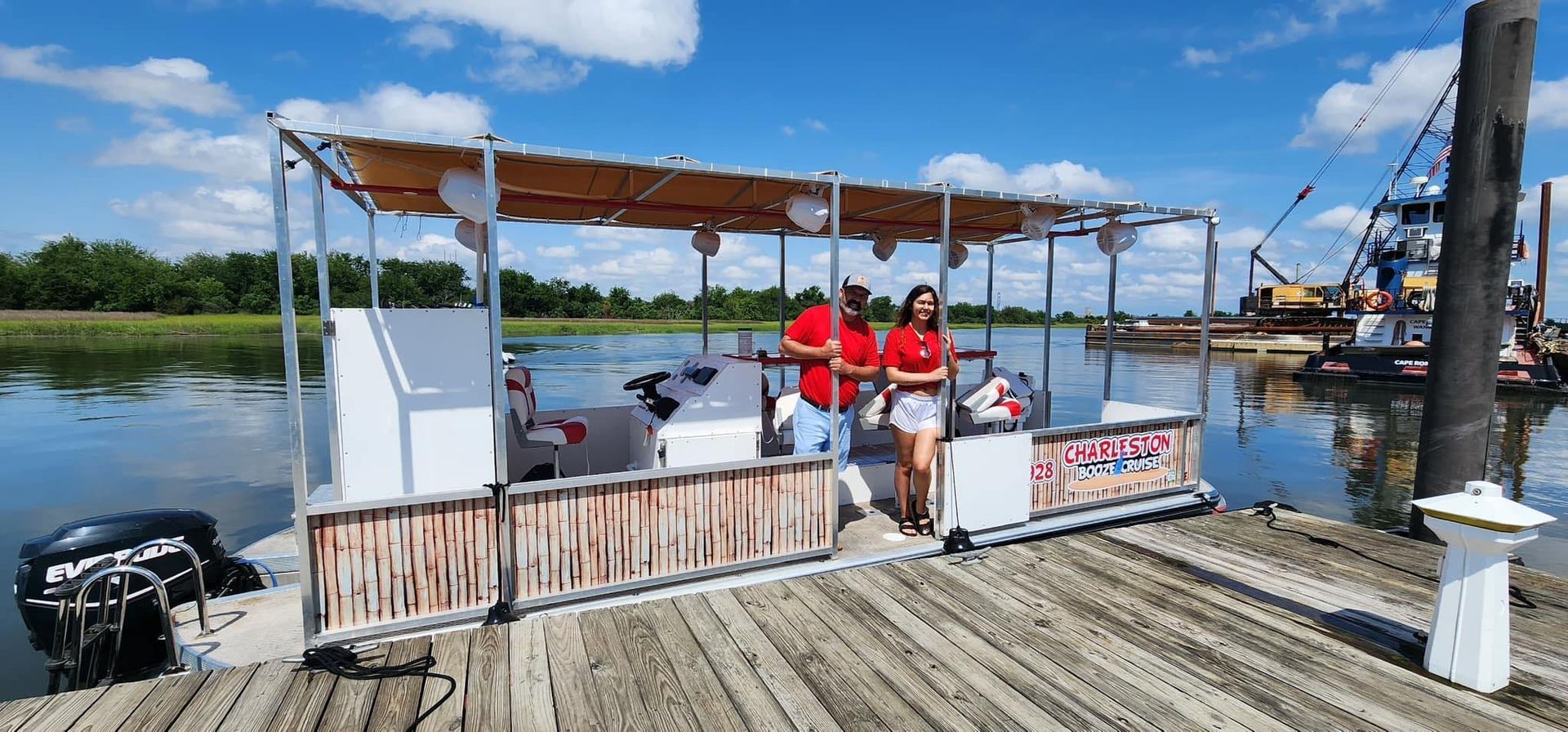 Two people are standing on a dock next to a boat.
