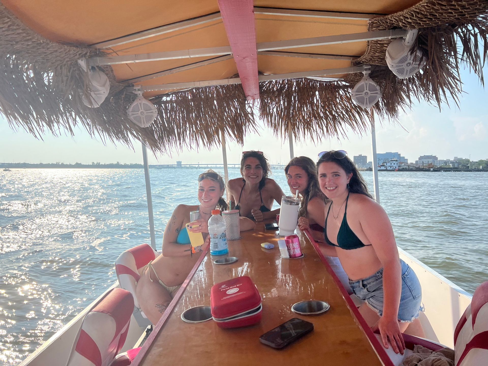 A group of women are sitting on a boat holding drinks.