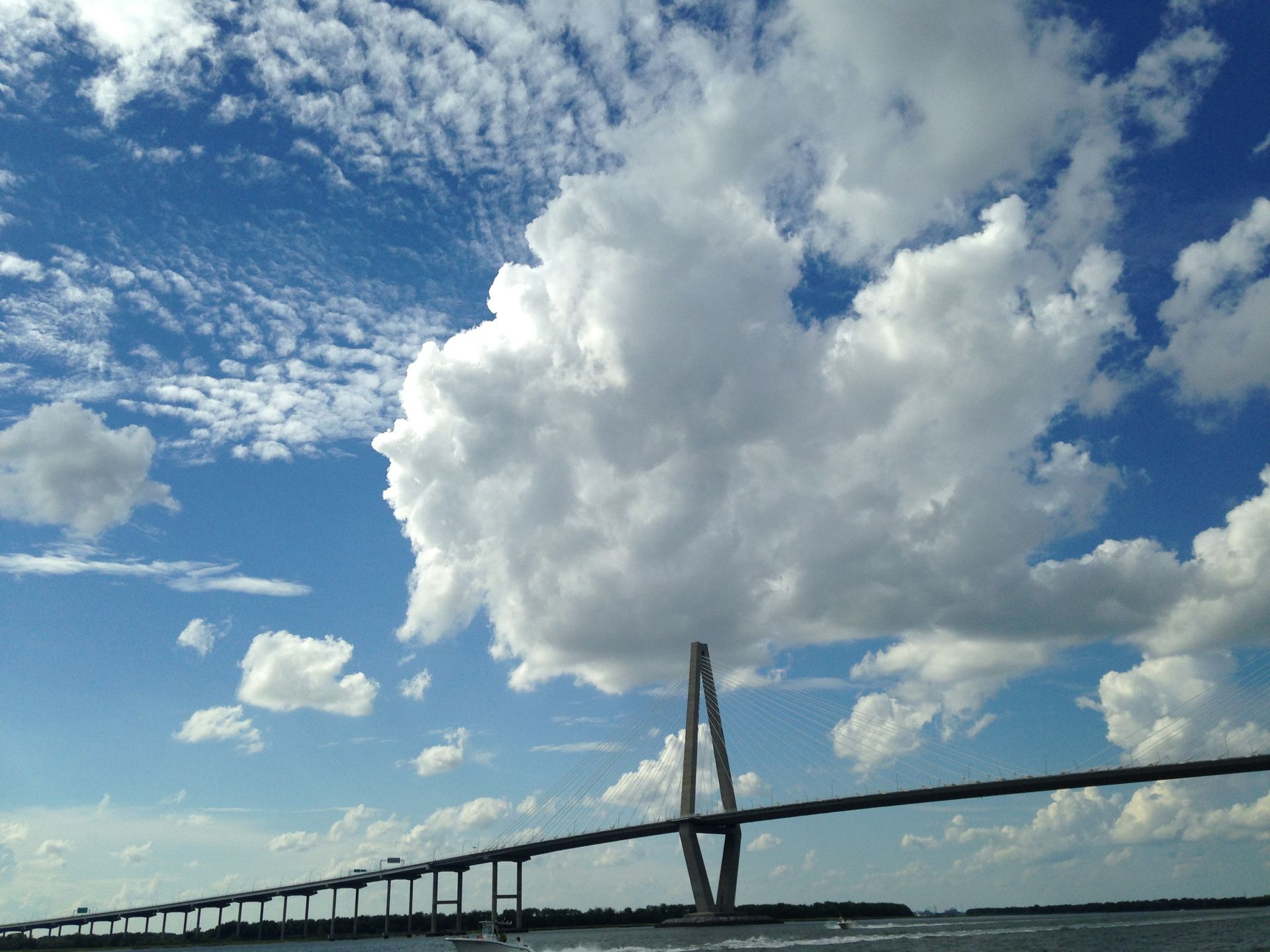 A bridge over a body of water with clouds in the sky.