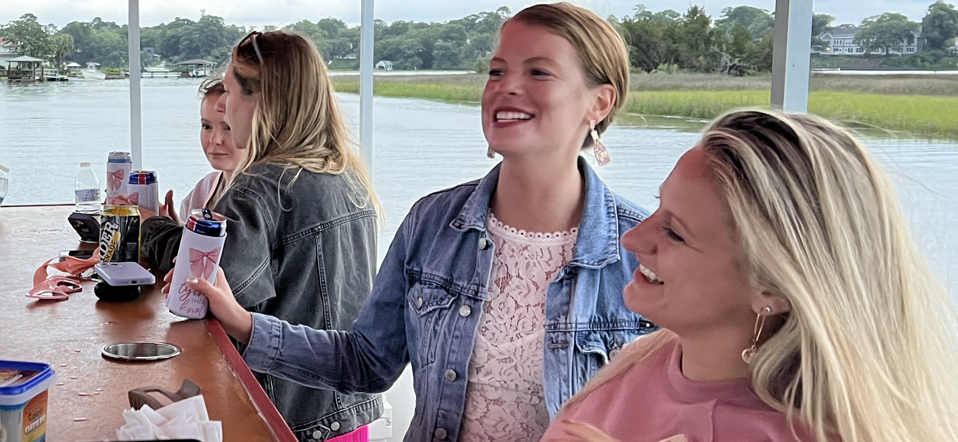 A group of women are sitting at a table in front of a body of water.